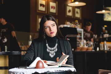 Portrait of a beautiful girl reading book in cafe