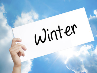 Winter Sign on white paper. Man Hand Holding Paper with text. Isolated on sky background