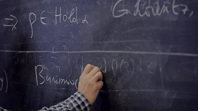 the hand writes on the blackboard a formula