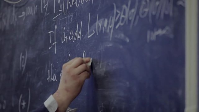 the hand writes on the blackboard a formula