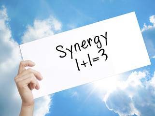 Synergy concept 1+1=3 Sign on white paper. Man Hand Holding Paper with text. Isolated on sky background