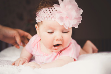 Cute sleeping beautiful and yawning baby girl in pink lying down on a white bed at home. Infant napping in bed. Healthy little kid shortly after birth.