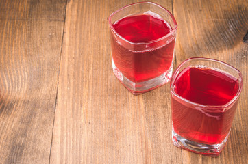 two glasses of red cocktail on wooden background/two glasses with red juice top view