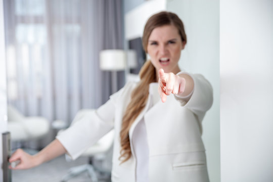 Angry woman standing in doorway pointing at camera
