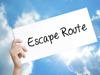 Escape Route Sign on white paper. Man Hand Holding Paper with text. Isolated on sky background
