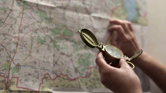 A young man prepares for a tourist trip, he uses a map and compass