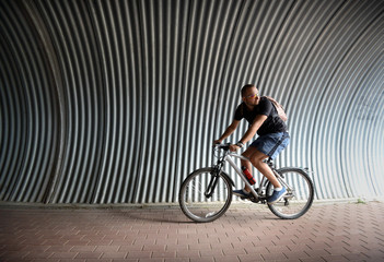 Fototapeta na wymiar Man cyclist stands on the bike path under the bridge
