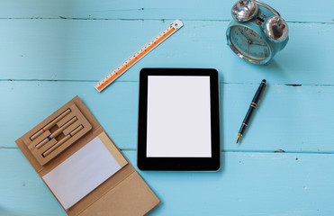 top view mock up tablet similar style on color wood , office tool book note and old alarm clock