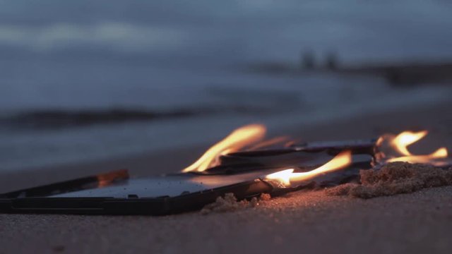 data cd dvd laser compact disc case on fire on the wet sand at coast HD