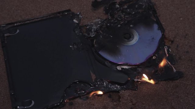 data cd dvd laser compact disc case on fire on the wet sand at coast HD
