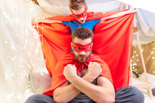 Father And Son In Superhero Costumes Playing Together In Blanket Fort