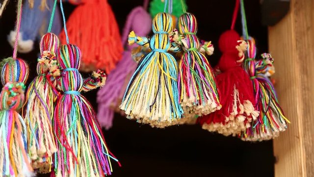 Colorful dolls hanging on strings. Dolls of women made of threads in souvenir shop