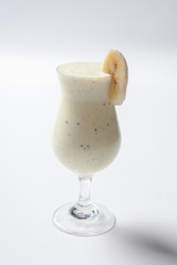 banana milkshake with a piece of banana in a tall glass
