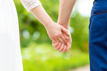 Newweds. Close up of loving couple holding hands in the park