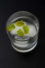 Top view of an iced glass with mint leaves, on dark background