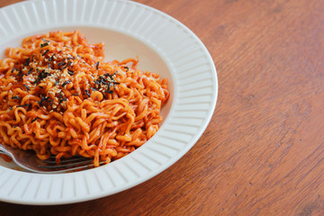 Spicy noodles sprinkle sesame seeds and seaweed on a wooden background.