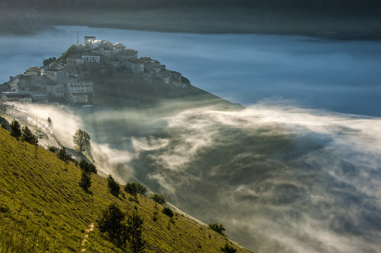 The town of Castelluccio di Norcia in the fog at sunset, Monti Sibillni NP, Umbria, Italy