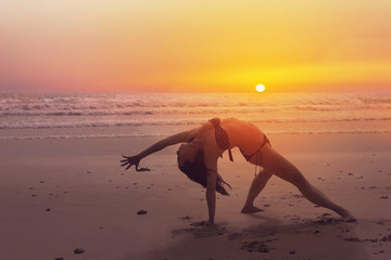 Woman doing a yoga pose on the beach at sunset