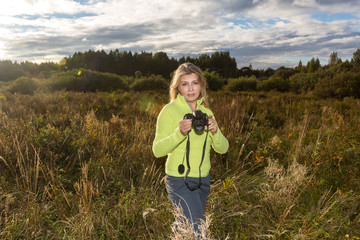 Pretty blonde woman makes photos on the camera outdoor