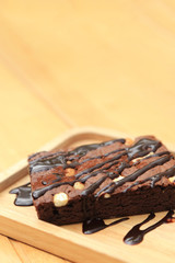 Homemade chocolate brownie on wooden plate with copy space.