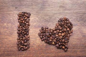 Heart made of coffee beans over wood background