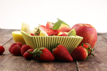Mixed fruit salad in the bowl on wooden background