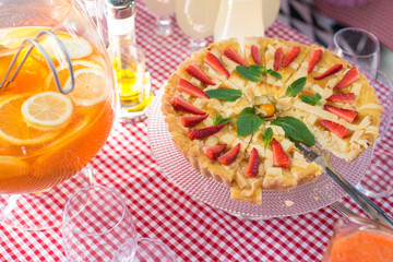 Fototapeta na wymiar Whole round apple pie decorated with strawberry on a glass stand