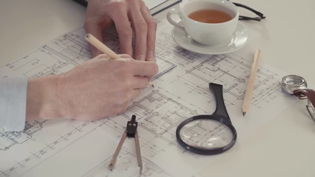 Architect sketching a construction project with pencil and ruler at work place.
