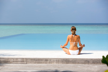 Fototapeta na wymiar Beautiful young lady meditating on a beach Maldives