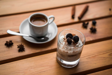 Dessert tiramisu with fruit on a wooden table with a cappuccino