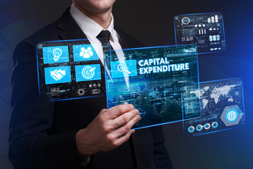 Business, Technology, Internet and network concept. Young businessman working on a virtual screen of the future and sees the inscription: Capital expenditure