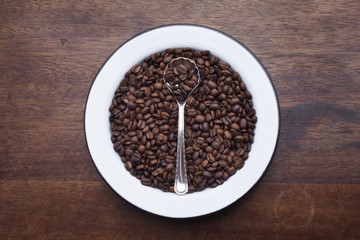 Plate with coffee beans over wooden background