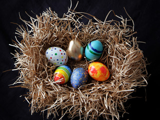 Fototapeta na wymiar Easter colorful eggs in the nest on black background.