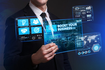 Business, Technology, Internet and network concept. Young businessman working on a virtual screen of the future and sees the inscription: Boost your business