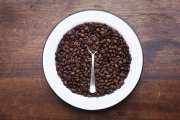 Plate with coffee beans over wooden background