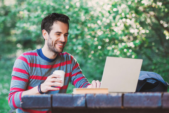 Young Man Working On A Laptop In The Park