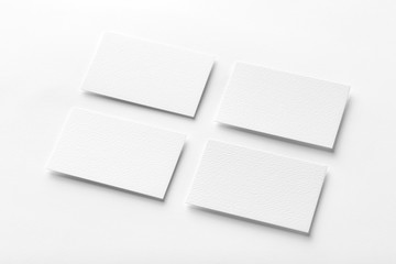 Mockup of four white business cards arranged in rows at white design paper background.
