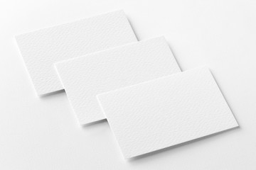 Mockup of three horizontal business cards at white textured background.