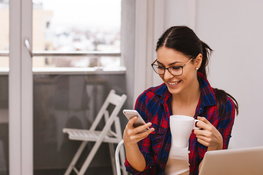 A Businesswoman Checking Email Via Mobile Phone And Holding A Coffee Cup Indoor