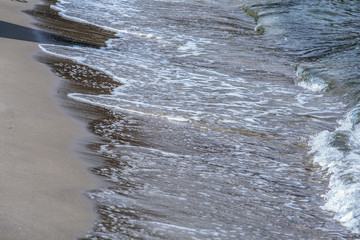 beautiful summer sand beach and sea surf. Stones and waves / Baltic Sea. Foamy wave Poland.