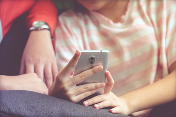 Woman hand using smart phone while sitting on sofa with her friend in casual lifestyle, vintage tone background, woman on phone concept