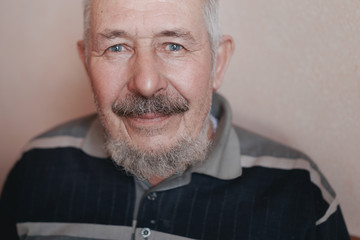 Portrait of old gray-haired smiling man with a beard and mustache.