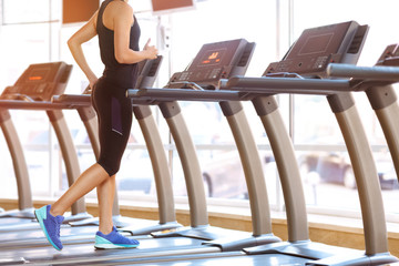 Fototapeta na wymiar Young athletic woman running on a treadmill at the gym