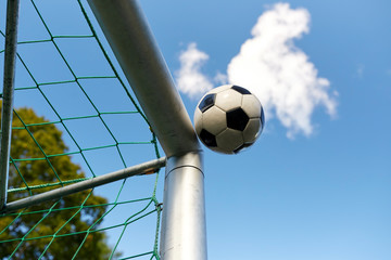soccer ball flying into football goal net over sky