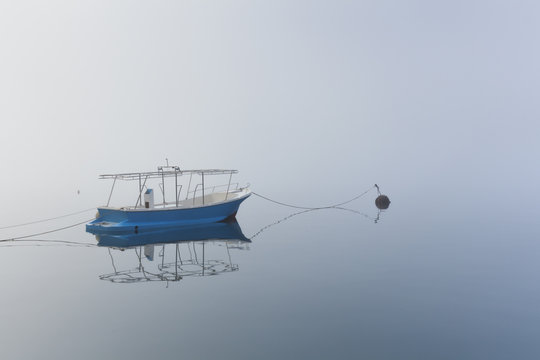 A boat anchored in the calm sea of the Bay of Kotor, Montenegro