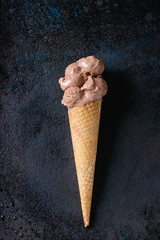 Chocolate ice cream mini balls in waffle cone over black metal texture background. Top view with space