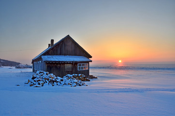 Деревянный дом на восходе солнца зимним утром на...