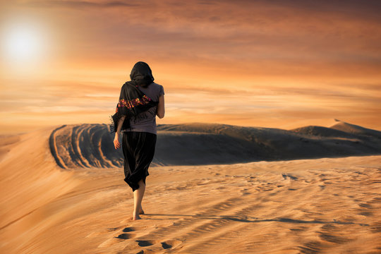 Frau in schwarz läuft in der Wüste bei Sonnenuntergang