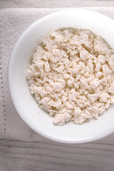 Cottage cheese in the ceramic plate on the white table vertical
