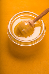 Honey on the glass bowl on the yellow background vertical